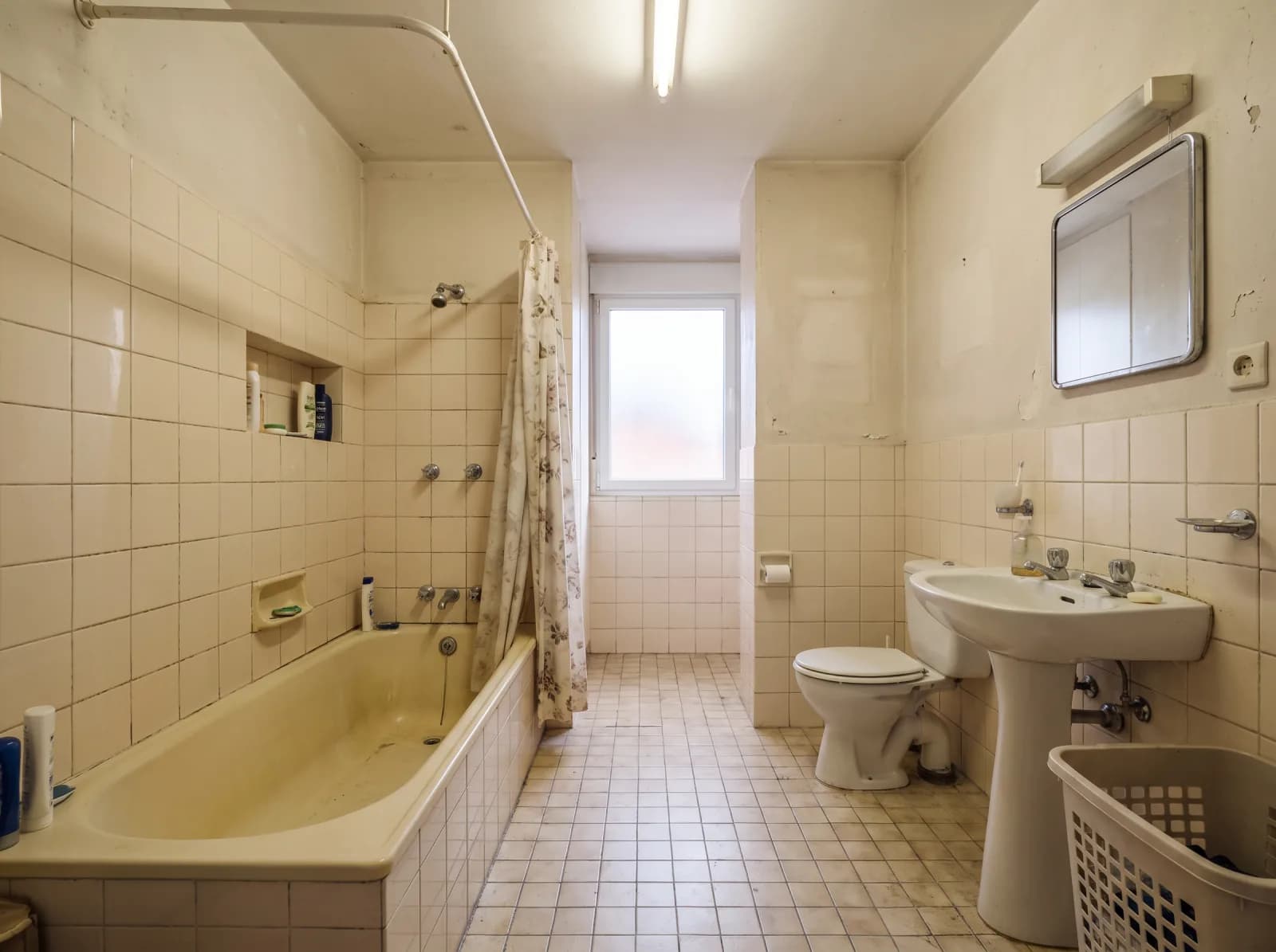 Baño antiguo con bañera acrílica y azulejos amarillentos antes del cambio a ducha en Triana, Sevilla