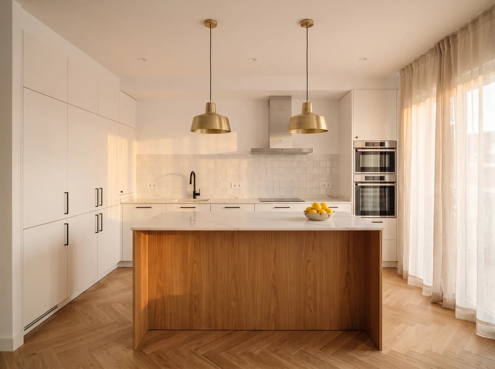 Cocina reformada por Vega Home en Nervión con encimera de cuarzo, isla central con roble, azulejo zellige y luminarias colgantes