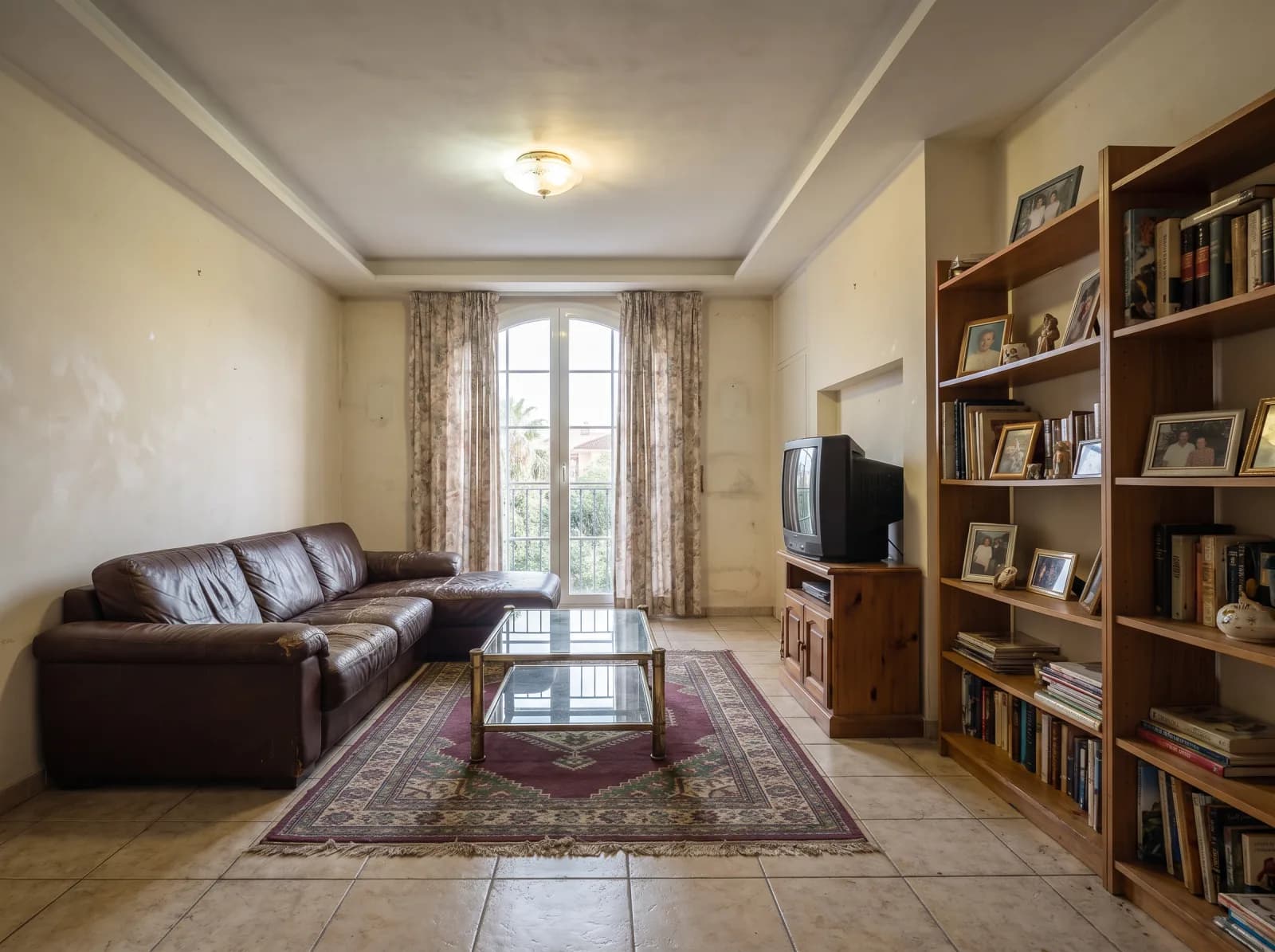 Salón antes de la reforma integral en Mairena del Aljarafe — sofá de cuero desgastado y muebles obsoletos